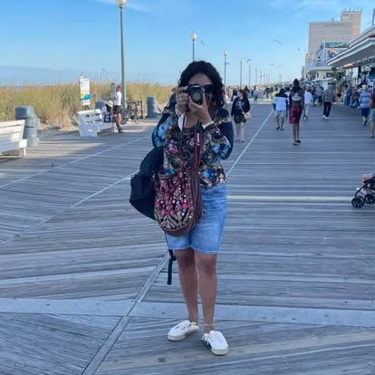 Darla Wolfe taking a photograph on a seaside boardwalk